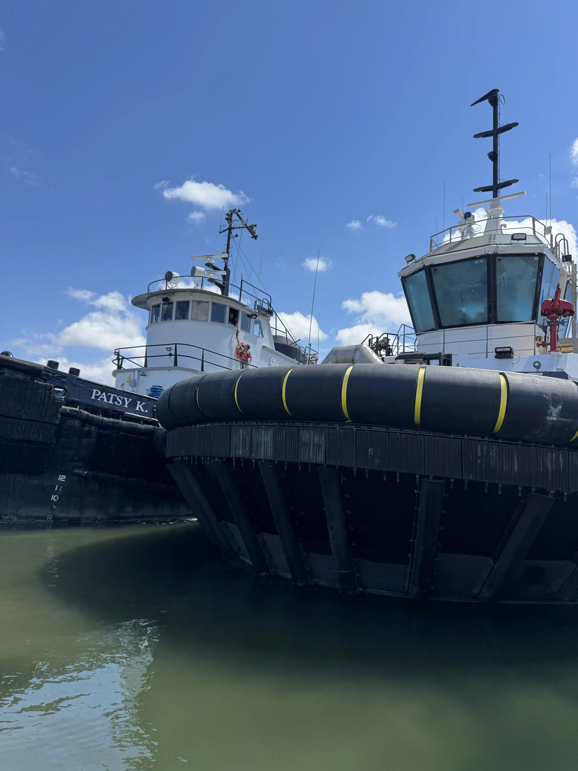 Two tugboats bow on at the dock, seen from the water